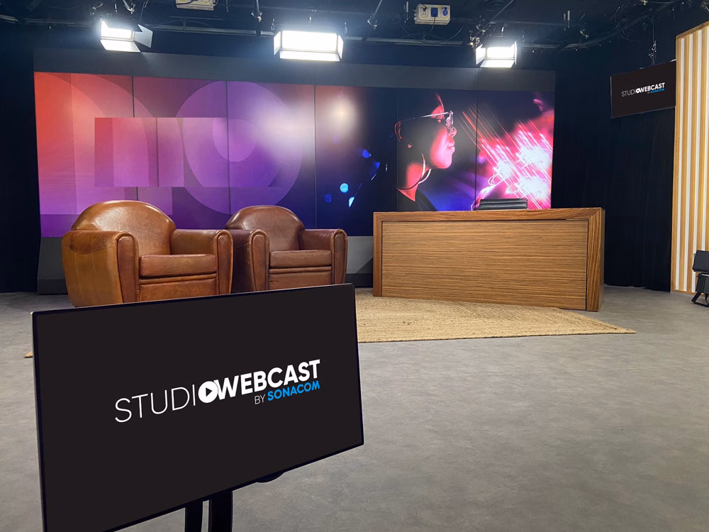 Plateau TV du Studio Webcast en configuration Late Show avec deux fauteuils club en cuir marron, bureau de présentateur en bois et fond LED